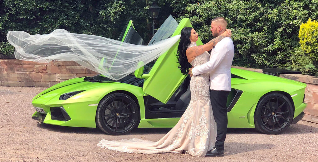 A wedding couple embracing in front of a Lamborghini Aventador.